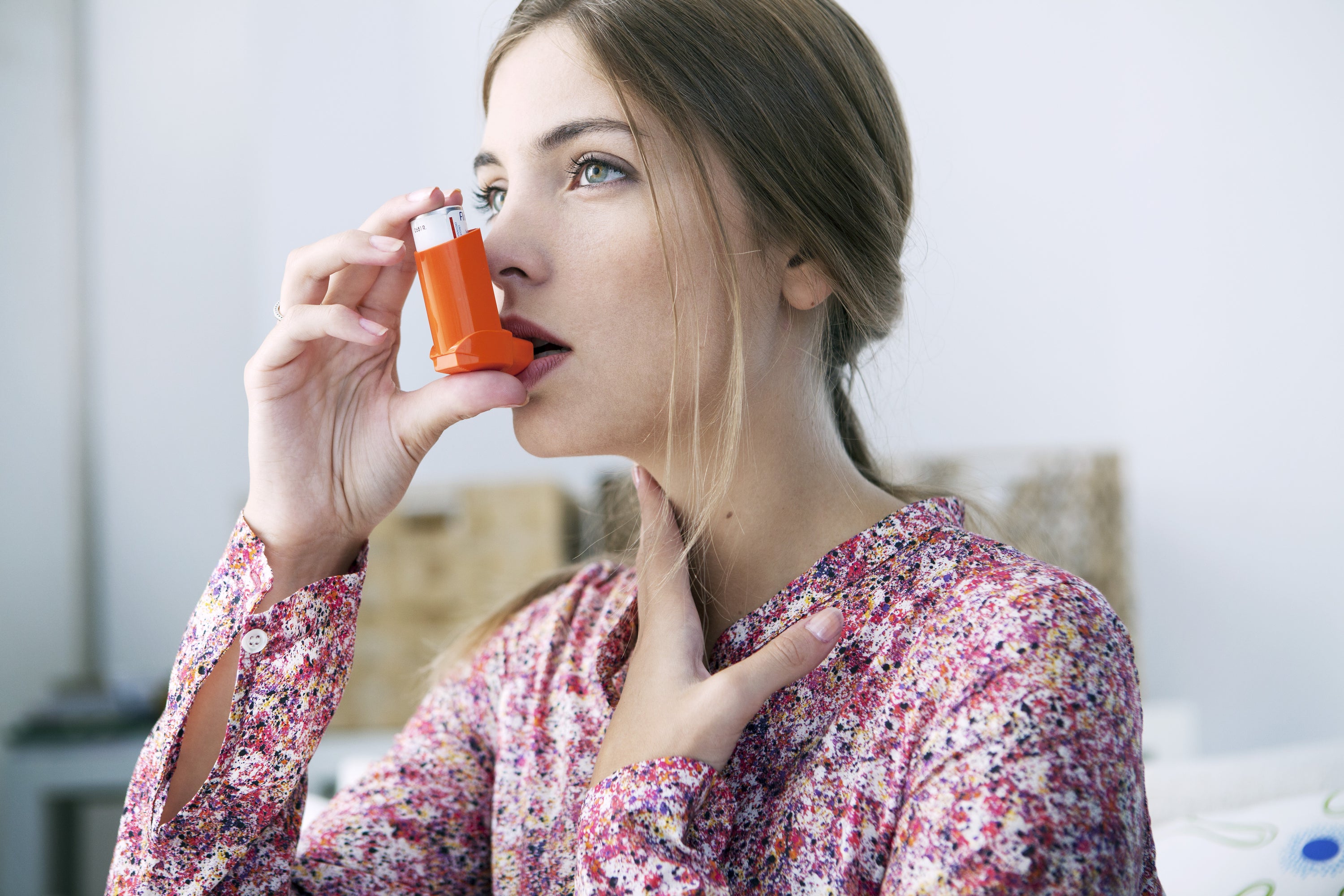 Image of a woman with asthma using an inhaler, managing her respiratory condition with proper medical care.